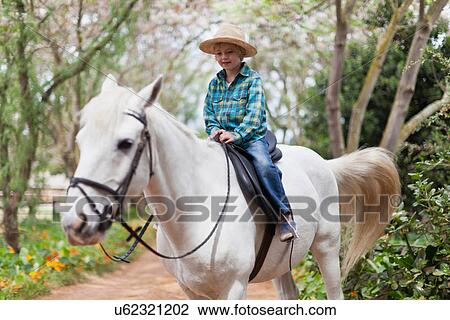 Smiling boy riding horse in park View Large Photo Image Stock Image - Smiling boy riding horse in park. Fotosearch