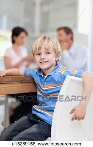 Smiling boy sitting at table View Large Photo Image Stock Photograph - Smiling boy sitting at table. Fotosearch