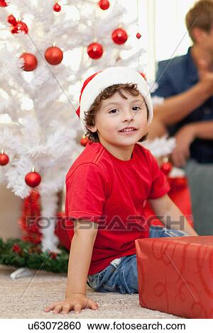 Smiling boy wearing Santa Claus hat View Large Photo Image Stock Image - Smiling boy wearing Santa Claus hat. Fotosearch