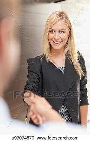 Stock Image - Smiling business people shaking hands. Fotosearch