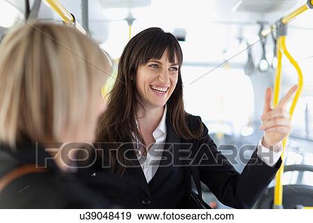 Stock Photo - Smiling businesswomen riding the bus. Fotosearch