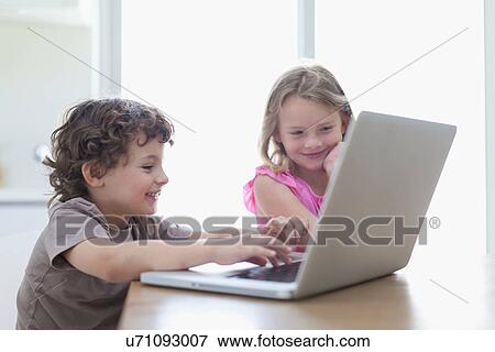 Smiling children using laptop together View Large Photo Image Stock Photo - Smiling children using laptop together. Fotosearch