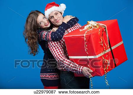 Stock Photo - Smiling couple carrying wrapped gift. Fotosearch