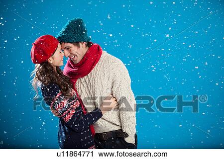 Stock Image - Smiling couple hugging in snow. Fotosearch