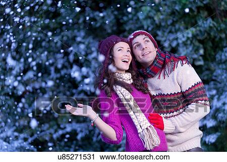 Stock Image - Smiling couple hugging in snow. Fotosearch