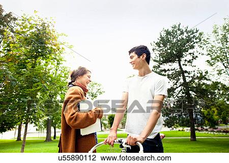 Stock Image - Smiling couple talking in park. Fotosearch