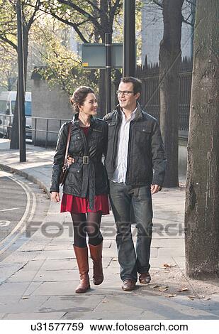 Smiling couple walking on city street View Large Photo Image Stock Photo - Smiling couple walking on city street. Fotosearch