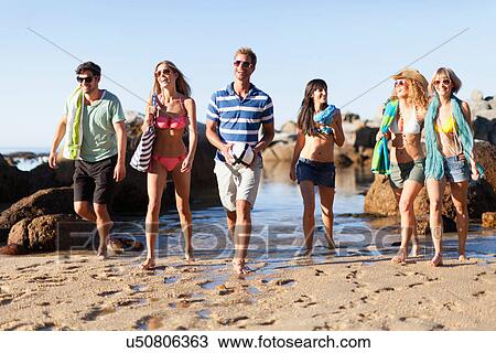 Stock Image - Smiling friends walking on beach. Fotosearch