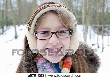 Stock Image - Smiling girl in braces and earmuffs. Fotosearch