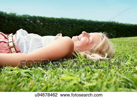 Smiling girl laying in grass View Large Photo Image Stock Image - Smiling girl laying in grass. Fotosearch