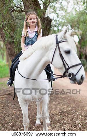 Smiling girl riding horse in park View Large Photo Image Stock Photo - Smiling girl riding horse in park. Fotosearch