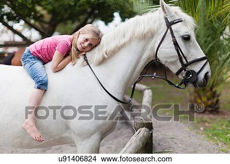 Picture - Smiling girl riding horse in yard. Fotosearch