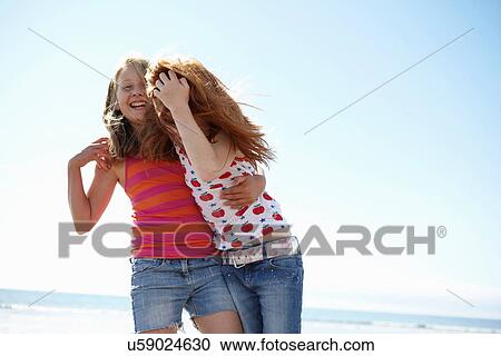 Smiling girls hugging on beach View Large Photo Image Stock Image - Smiling girls hugging on beach. Fotosearch