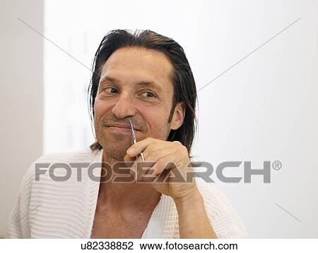 Stock Image - Smiling man clipping nose hairs. Fotosearch