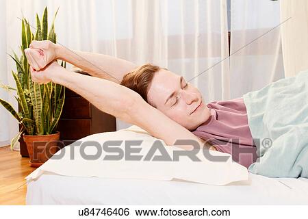 Smiling man stretching in bed View Large Photo Image Stock Photograph - Smiling man stretching in bed. Fotosearch