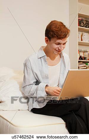 Smiling man using laptop in living room View Large Photo Image Picture - Smiling man using laptop in living room. Fotosearch