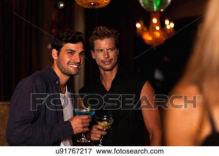 Stock Photo - Smiling men having cocktails in club. Fotosearch
