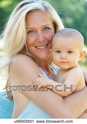 Smiling mother holding baby outdoors View Large Photo Image Stock Image - Smiling mother holding baby outdoors. Fotosearch
