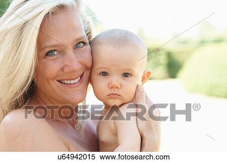Smiling mother holding baby outdoors View Large Photo Image Stock Photography - Smiling mother holding baby outdoors. Fotosearch