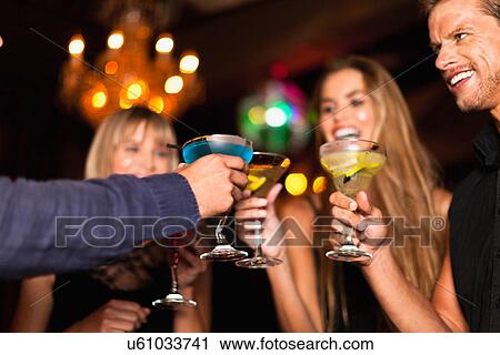 Stock Image - Smiling people having cocktails in club. Fotosearch