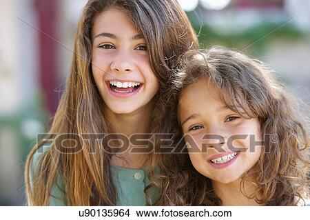 Smiling sisters hugging outdoors View Large Photo Image Picture - Smiling sisters hugging outdoors. Fotosearch