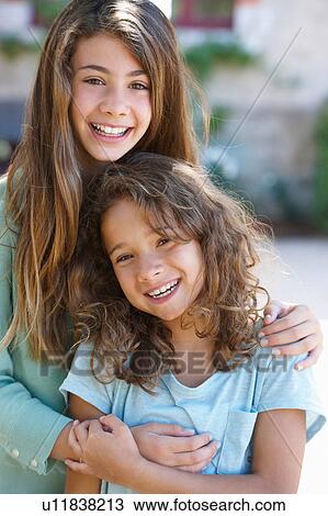 Smiling sisters hugging outdoors View Large Photo Image Stock Image - Smiling sisters hugging outdoors. Fotosearch