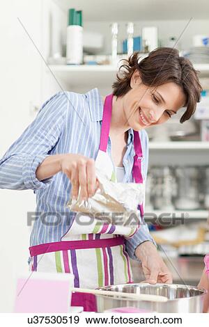 Stock Photo - Smiling woman baking in kitchen. Fotosearch