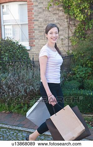 Stock Photo - Smiling woman carrying shopping bags. Fotosearch