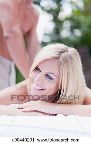 Stock Image - Smiling woman having massage outdoors. Fotosearch