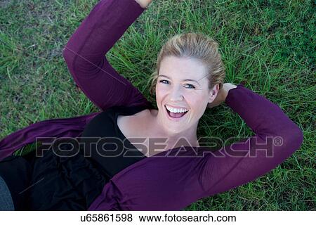 Smiling woman laying in grass View Large Photo Image Stock Photo - Smiling woman laying in grass. Fotosearch