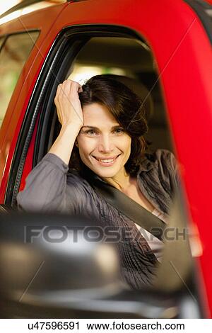 Stock Image - Smiling woman leaning out of car. Fotosearch