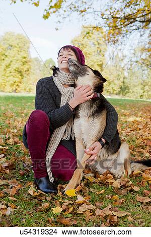 Smiling woman petting dog in park View Large Photo Image Picture - Smiling woman petting dog in park. Fotosearch