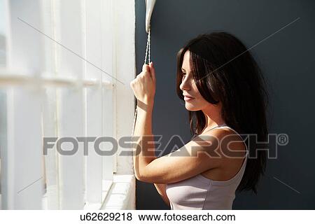 Stock Photo - Smiling woman raising blinds. Fotosearch
