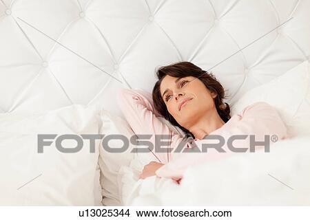 Picture - Smiling woman relaxing in bed. Fotosearch