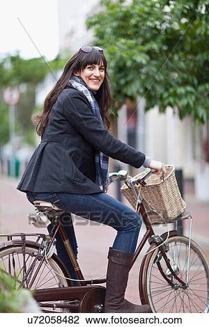 Smiling woman riding bicycle in city View Large Photo Image Stock Image - Smiling woman riding bicycle in city. Fotosearch