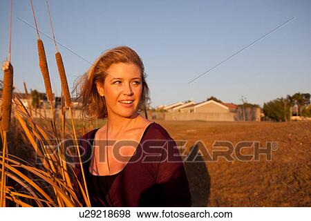 Smiling woman standing in wheat field View Large Photo Image Stock Photo - Smiling woman standing in wheat field. Fotosearch