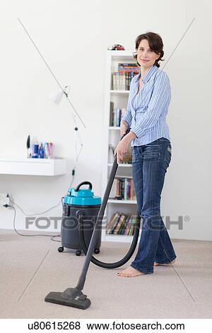 Smiling woman vacuuming living room View Large Photo Image Stock Photo - Smiling woman vacuuming living room. Fotosearch