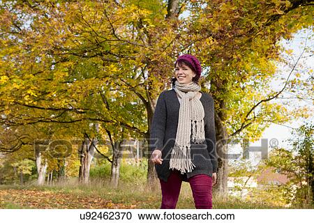 Stock Image - Smiling woman walking in park. Fotosearch