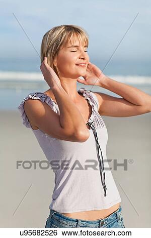 Stock Photograph - Smiling woman walking on beach. Fotosearch