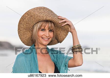 Smiling woman wearing straw hat on beach View Large Photo Image Stock Image - Smiling woman wearing straw hat on beach. Fotosearch