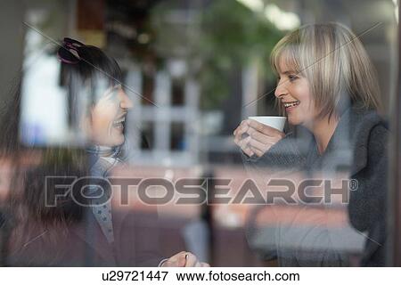 Stock Photo - Smiling women having coffee in cafe. Fotosearch