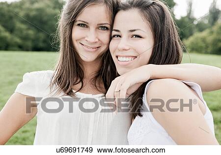 Stock Photo - Smiling women hugging outdoors. Fotosearch