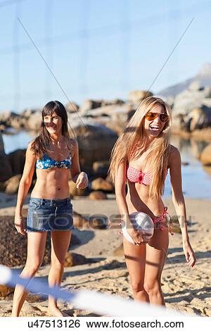 Stock Photograph - Smiling women playing beach volleyball. Fotosearch