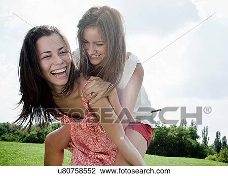 Stock Image - Smiling women playing outdoors together. Fotosearch