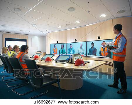 Staff members in meeting room with colleagues on video conference screens View Large Photo Image Stock Photo - Staff members in meeting room with colleagues on video conference screens. Fotosearch