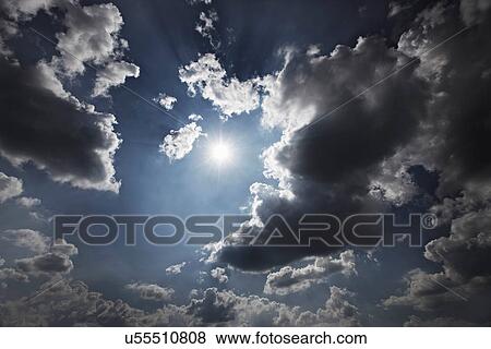 Stock Photo - Sun and clouds in blue sky. Fotosearch