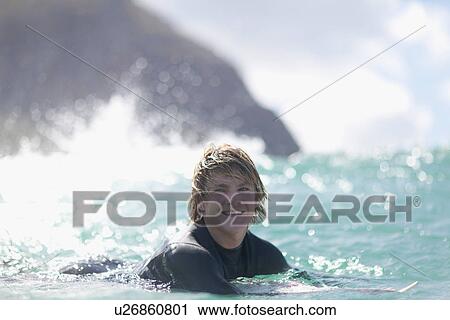 Stock Image - Surfer paddling in water. Fotosearch