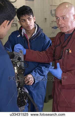 Teacher helping students with car engine View Large Photo Image Stock Photography - Teacher helping students with car engine. Fotosearch