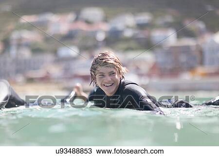 Stock Image - Teenage boy paddling with surfboard. Fotosearch