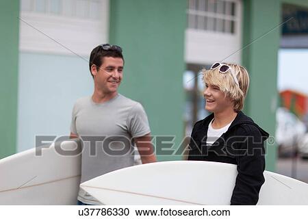 Stock Image - Teenage boys carrying surfboards. Fotosearch